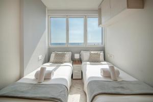 two beds in a room with a window at You Stylish Beach Apartments in Barcelona