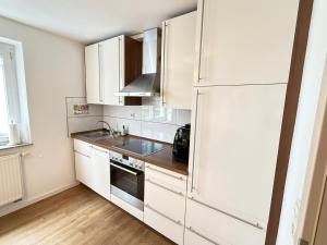 a kitchen with white cabinets and a refrigerator at Appartement Turan in Friedrichshafen