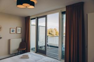 a bedroom with a bed and a large window with a balcony at Herenhuis geschakeld | 8 personen - Boutique Parc Pharshoeke in Heeg +48 photos