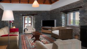 a living room with a stone wall at Casa das Marias in Ponta do Pargo