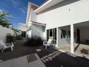 a white house with two white chairs in the yard at Beachside escape in Kuala Terengganu, Malaysia in Kampong Cherong Baru
