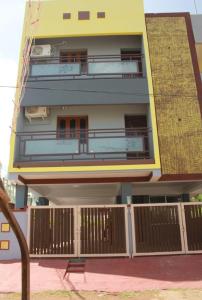 a tall yellow building with a fence in front of it at RK Home in Madurai