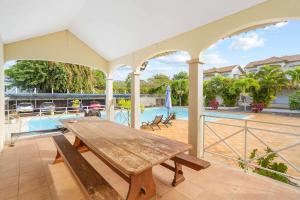 a wooden table on a patio with a pool at Serenity Bay - Perfect Tropical Stay in Pointe aux Cannoniers