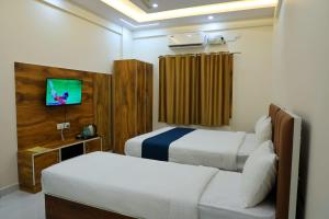 a hotel room with two beds and a tv at Hotel jetway in Muthugadahalli