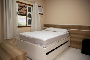 Un dormitorio con una cama blanca con una ventana. en Chale com lazer completo nas Montanhas, en Vítor Hugo