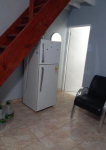 a kitchen with a white refrigerator and a black chair at Duplex En Iguazu in Puerto Iguazú