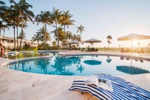 a large swimming pool with palm trees in the background at Tangalooma Sands in Tangalooma