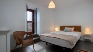 a bedroom with a bed and a chair and a window at Casa das Marias in Ponta do Pargo +20 photos