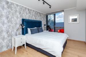 una camera da letto con un letto grande con testiera blu di Stylish Cape Town Penthouse a Città del Capo