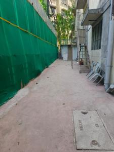 an empty alley with a green wall next to a building at Vyavasthapan hostels in Pune