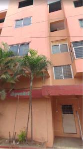 a pink building with palm trees in front of it at Vyavasthapan hostels in Pune