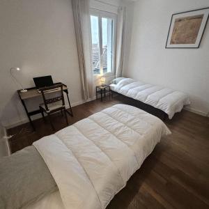 トノン・レ・バンにあるAppartement de charme au cœur de Thononのデスク、窓が備わるドミトリールームのベッド2台分です。