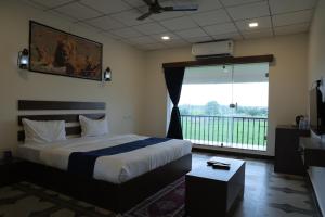 a bedroom with a bed and a large window at VITS Select Diamond Resort Sasan Gir in Talala