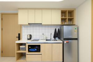 a kitchen with white cabinets and a stainless steel refrigerator at Fantasea Condo Kamala B211 2BDRM by Phuket Sabay Rent in Kamala Beach