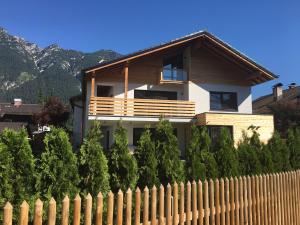 a house behind a fence with mountains in the background at Kandahar Lodge in Garmisch-Partenkirchen