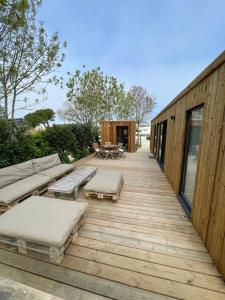 a wooden deck with a couch and a table at Lodge T4 - Chalet proche de la mer in La Brée-les-Bains