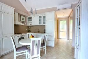 a kitchen with white cabinets and a table and chairs at Boka Kotorska Apartmani in Gornji Orahovac