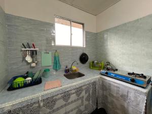 un comptoir de cuisine avec un évier et une cuisinière dans l'établissement CSG Homestay Kota Marudu, à Kampong Sorosob