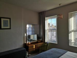 une chambre avec un lit et un bureau avec une télévision dans l'établissement Faith Cottage, à Brampton