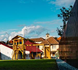 a playground in front of a building with a fence at FLH - Citadel Garden - Casă cu Curte și Parcare Privată lângă Cetatea Alba Carolina - Loc de Joacă și Ciubăr in Alba Iulia