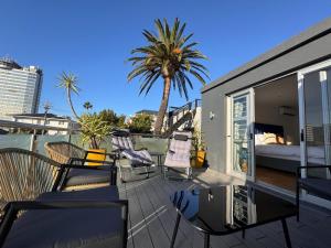 a balcony with chairs and a bed and a palm tree at Urban Oasis Penthouse-Jacuzzi! in Cape Town