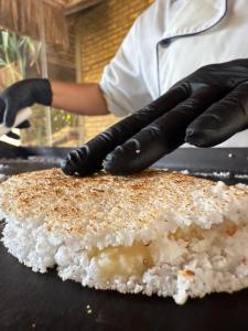 a person wearing black gloves preparing food on a grill at Pousada Império do Sol in Pipa +38 photos