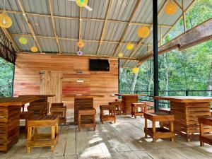 a restaurant with wooden tables and chairs and a flat screen tv at Riverston Water Front Villa in Rattota