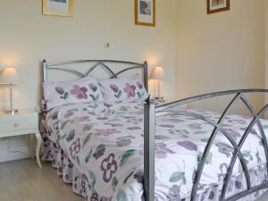 a bedroom with a bed with a floral bedspread at Maesmor in Bala +8 photos