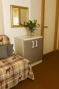 ein Schlafzimmer mit einem Bett und einer Kommode, auf der eine Pflanze steht in der Unterkunft Artesina in Sella della Turra
