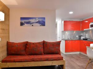 a living room with a red couch and a kitchen at Appartement rénové et tout confort au cœur de la station - FR-1-181-906 in Plagne Bellecote +5 photos