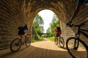tre persone in bicicletta attraverso un tunnel di Gîte "Le temps d'une pause" terrasse et piscine a Coubon