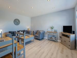 a living room with a couch and a tv at Goose Green Cottage in Snettisham