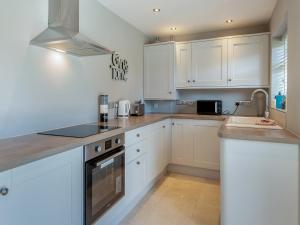 a small kitchen with white cabinets and a sink at Goose Green Cottage in Snettisham