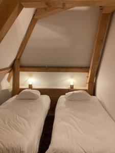 two beds in a attic room with white sheets at Le Moulin de la Doltière in Châteauvieux