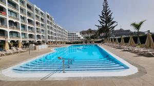a swimming pool in front of a large building at Cura Marina Premium in Playa del Cura