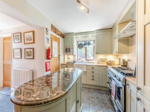 a kitchen with green cabinets and a marble counter top at Egmont Farmhouse in Newenden