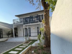 a white house with a tree in front of it at The Amaryllis Guest House in Mariental