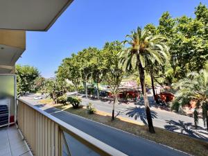 a balcony with a view of a street with palm trees at Studio Moderno Lungo Mare-ideale inverno in Menton