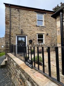 un panneau sur une clôture devant une maison dans l'établissement Ivy Cottage, à Low Eskcleth