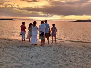 a family standing on the beach watching the sunset at Club Cantamar Beach Hotel & Marina in La Paz