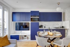 a kitchen with blue cabinets and a table with chairs at TBS 338 - Superb studio in Vincennes in Vincennes