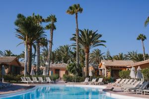 a pool at the resort with chairs and palm trees at Maspalomas Resort by Dunas in Maspalomas +45 photos