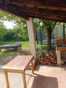 a picnic table and a pile of logs under a tree at Villa Bel Air in Saint-Étienne-les-Orgues