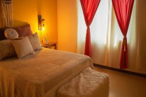 a bedroom with a bed with red curtains and a window at Casa Rural Bella Zaira in El Calafate
