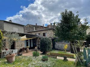 an old stone house with a garden in front of it at Ultimo Piano in Murlo