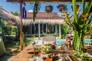ein Tisch mit Essen und Getränken auf einer Terrasse mit Pool in der Unterkunft Lila Boutik Residence in Canggu