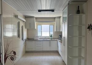 a large kitchen with white cabinets and a window at Casa de Praia in Palhoça