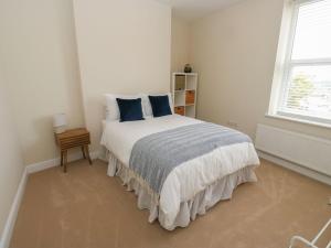 Un dormitorio blanco con una cama con almohadas azules. en 11 Bronte Street, en Haworth