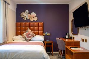 a hotel room with a bed and a desk and a tv at The Conningbrook Hotel in Ashford