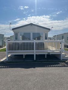 ein weißes Haus mit einer Veranda und einem weißen Geländer in der Unterkunft Spacious 10 birth Caravan Golden palm resort chapel st leonards Skegness in Chapel Saint Leonards